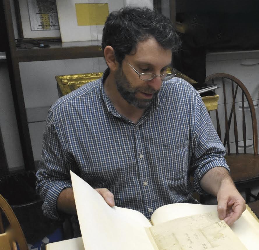 Dr. Scott Paul Gordon seated reading an archival document.